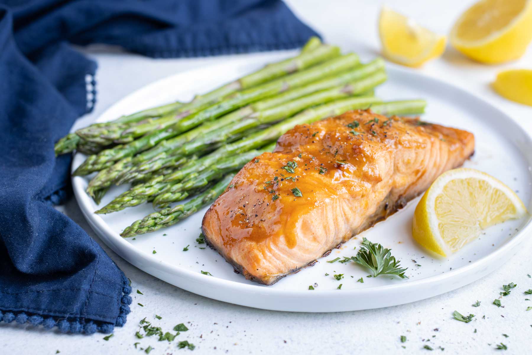 Honey mustard air fryer salmon served with asparagus and fresh lemon on a white plate.