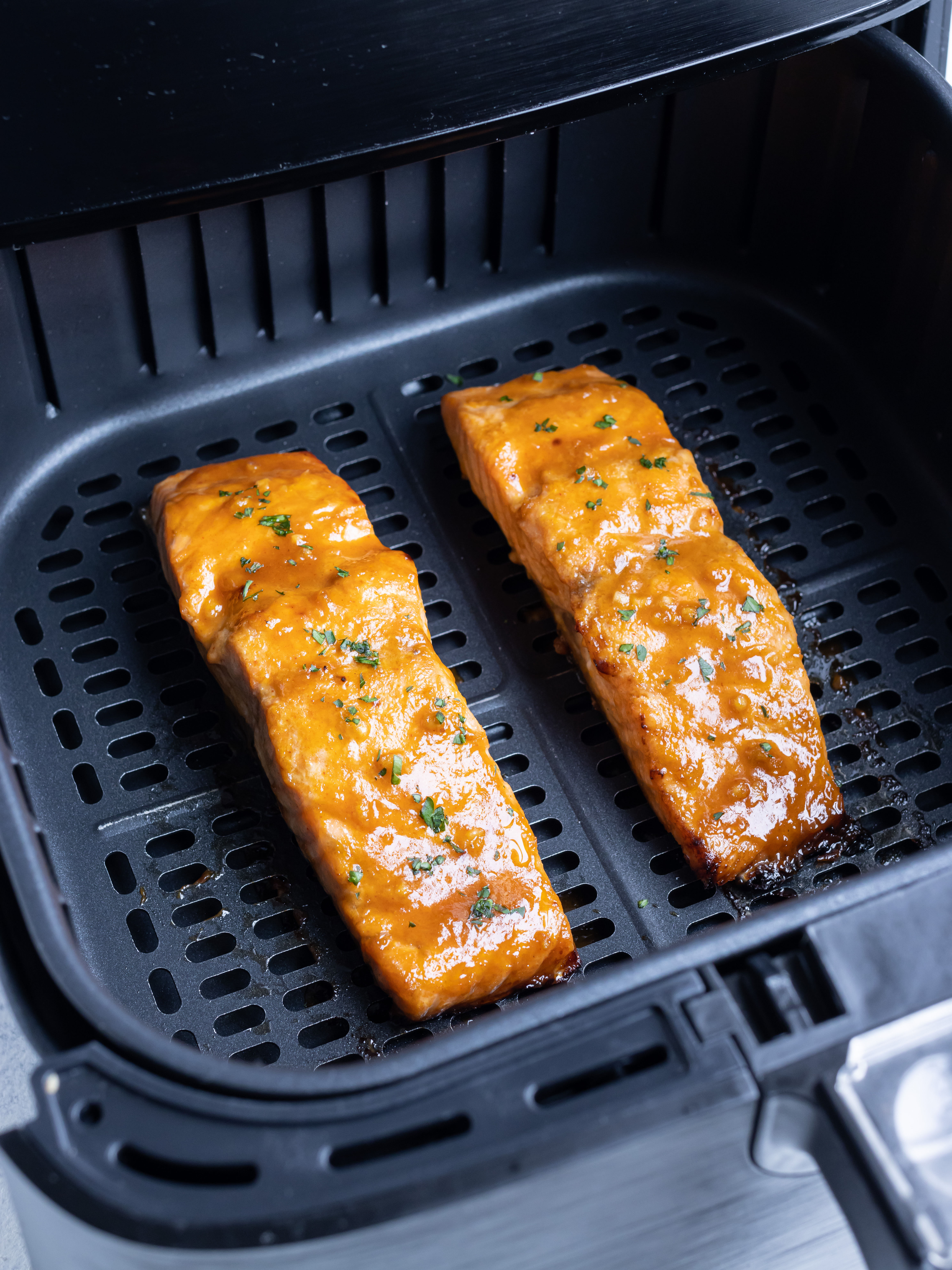 Two pieces of salmon are cooked in the air fryer.