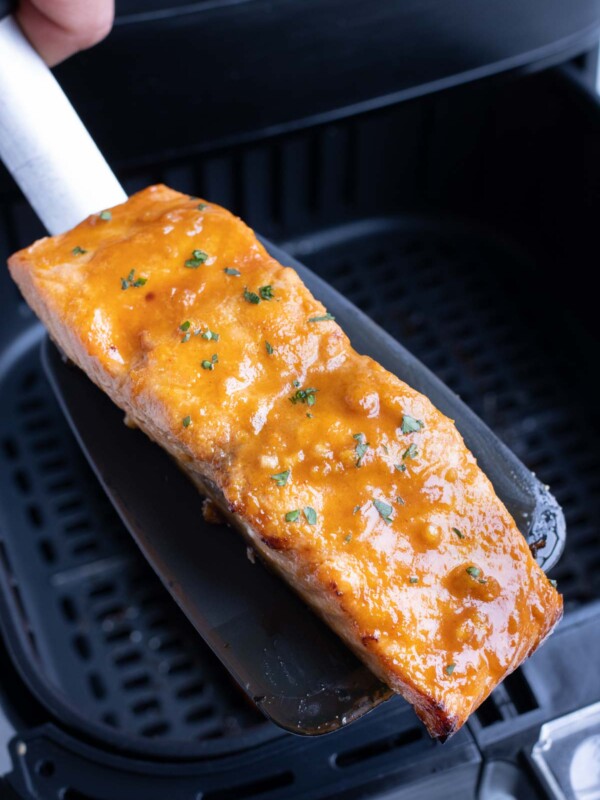 A spatula is used to remove the salmon from the air fryer.