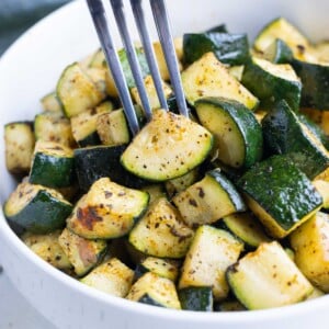 A fork lifts a piece of crispy air fryer zucchini made with no breading.