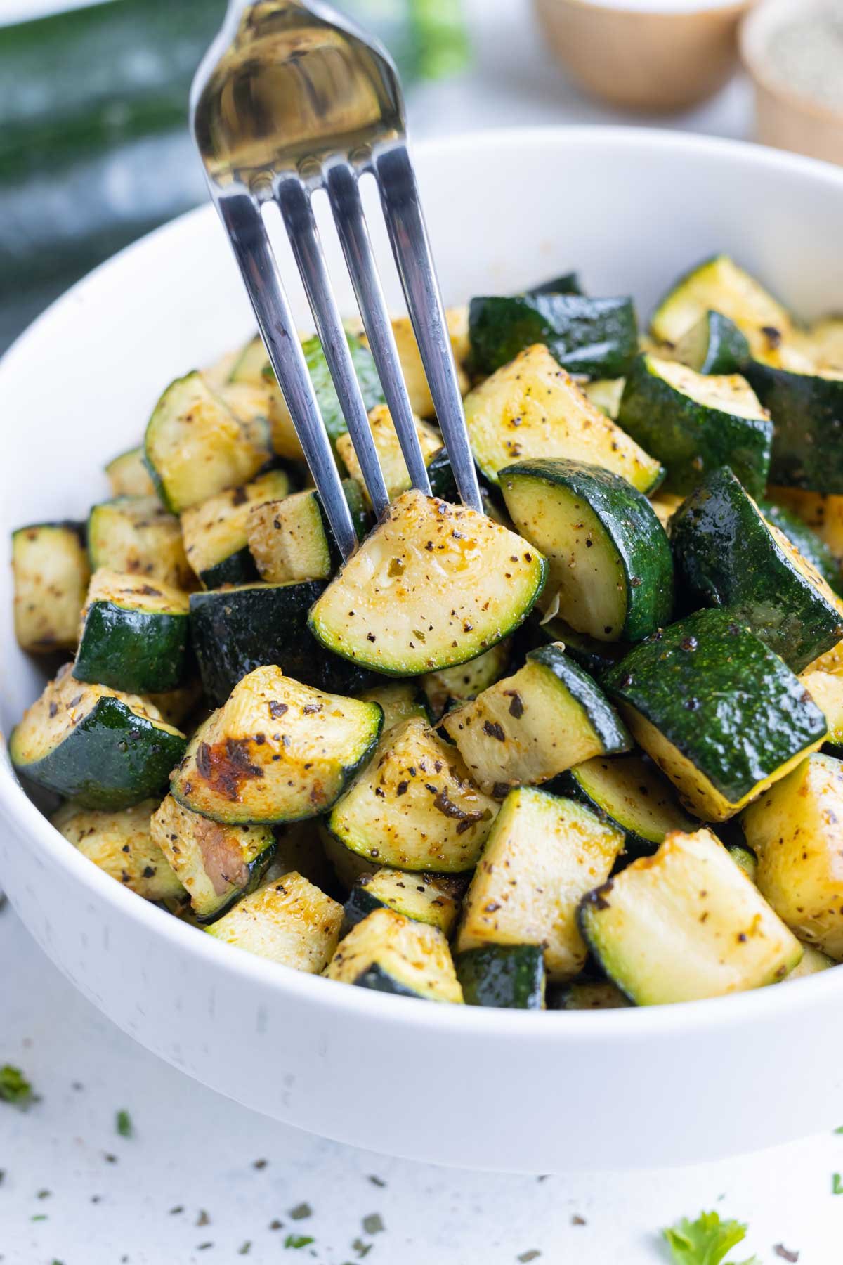 A fork pierces a piece of air fried zucchini.