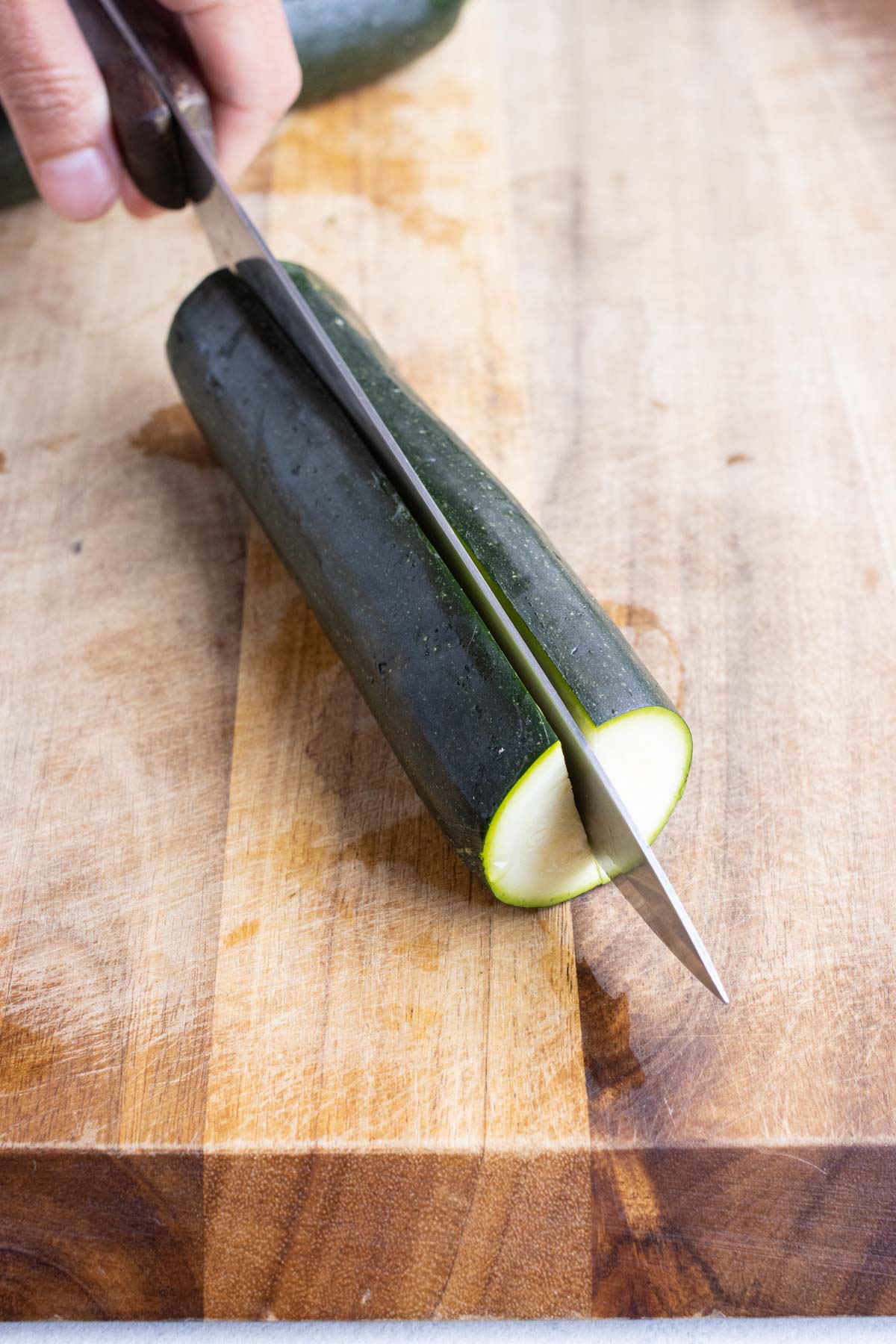 Showing how to slice a zucchini in half.