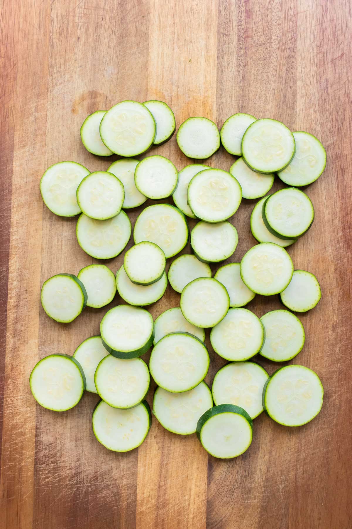 Zucchini slices are laid out flat on the cutting board.