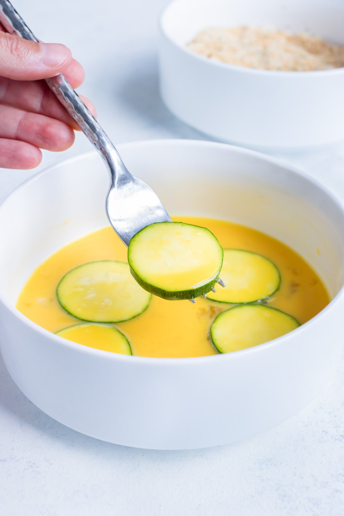 Zucchini chips are dipped in an egg mixture before being coated in breadcrumbs.