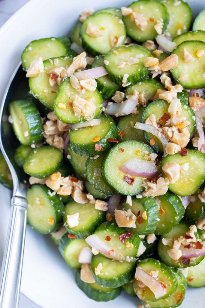 Cucumber salad in a bowl with a serving spoon.