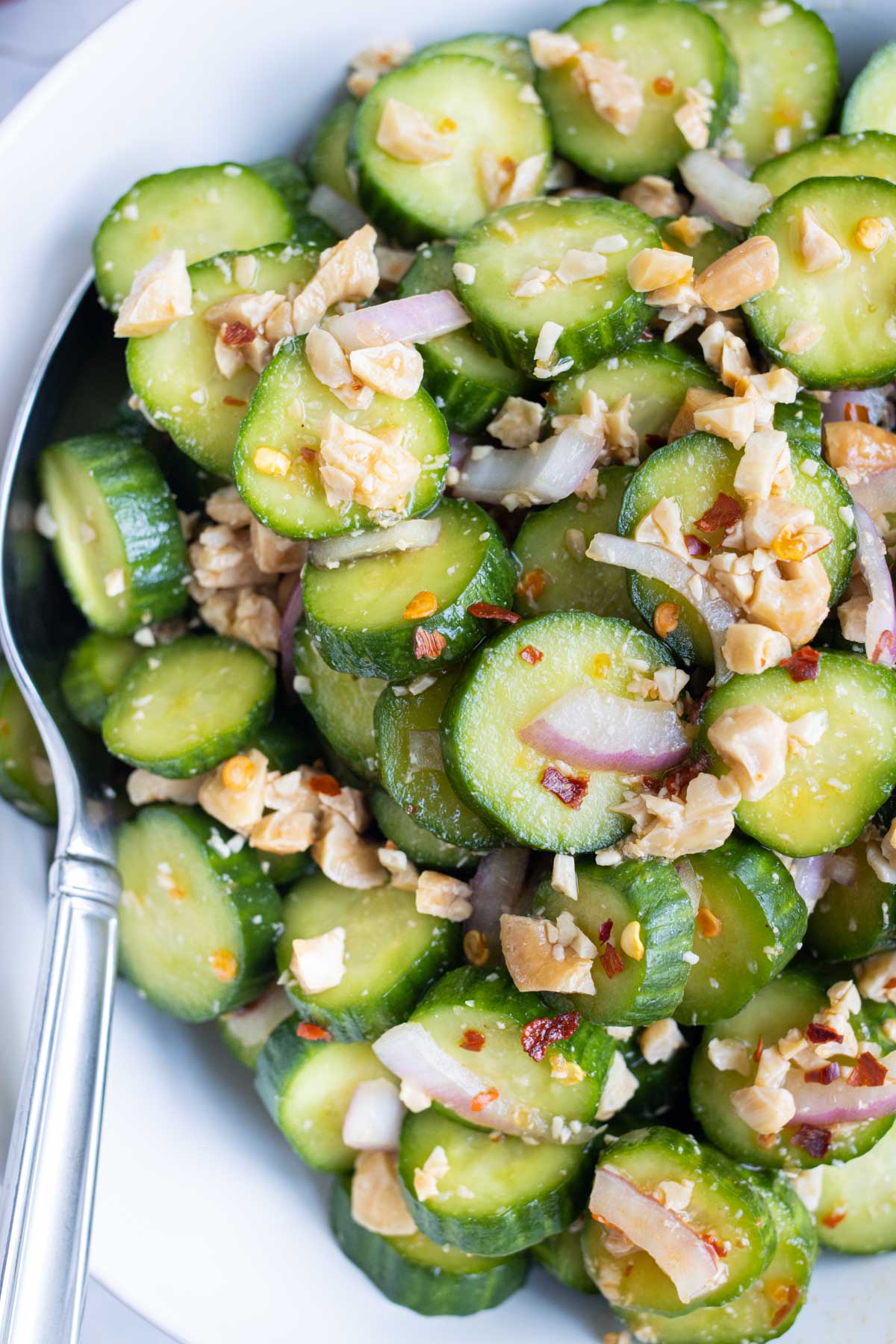 Quick Asian Cucumber Salad RECIPE served in a white dish with a silver spoon.