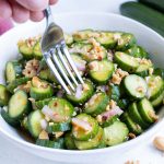 Delicious and flavorful cucumbers with dressing with a fork in a bowl.