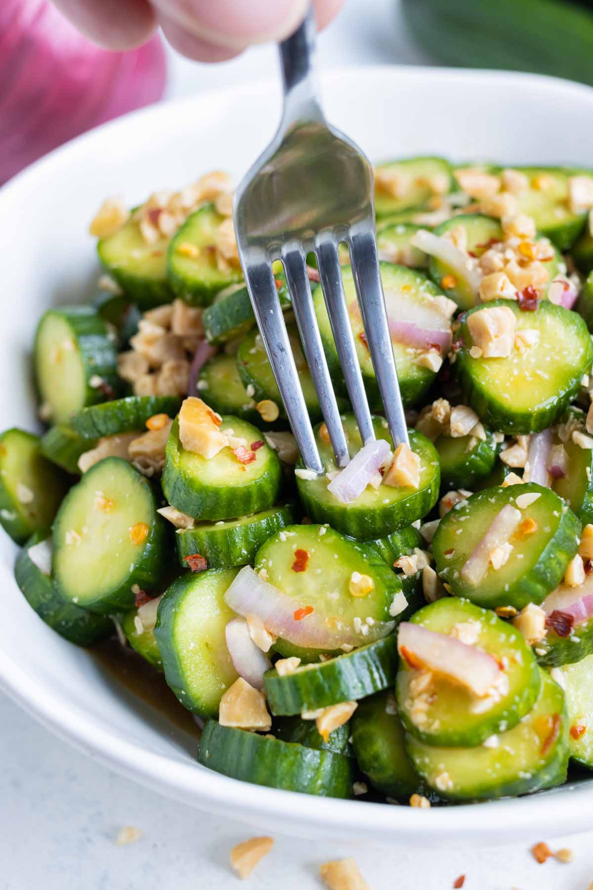 A fork digs into a bowl of Asian Cucumber Salad.