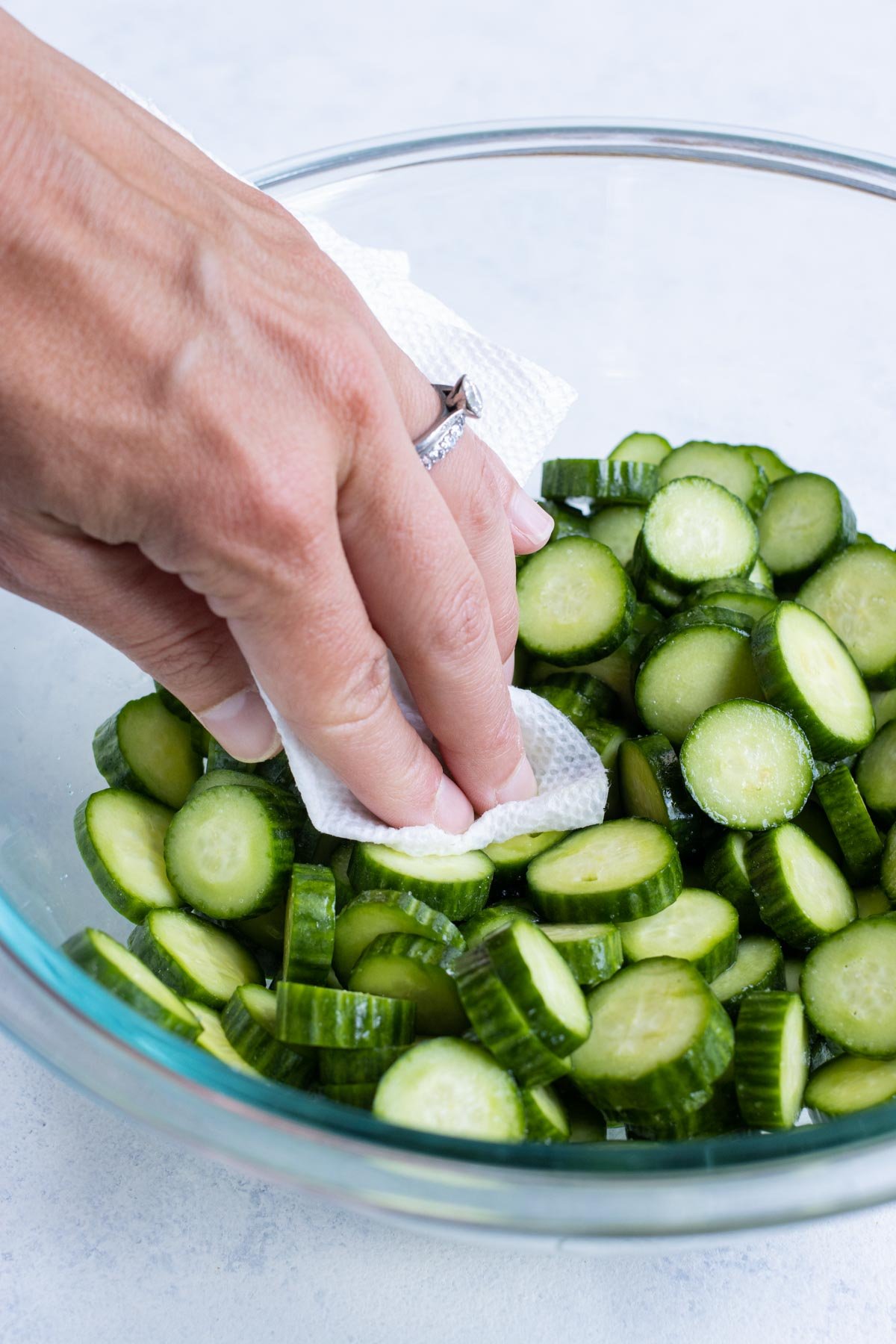 A paper towel is used to remove excess moisture from sliced cucumbers.