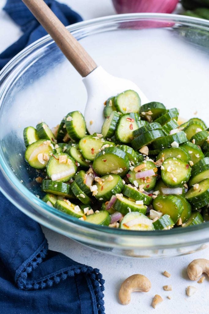 Sliced cucumbers and dressing in a glass bowl.