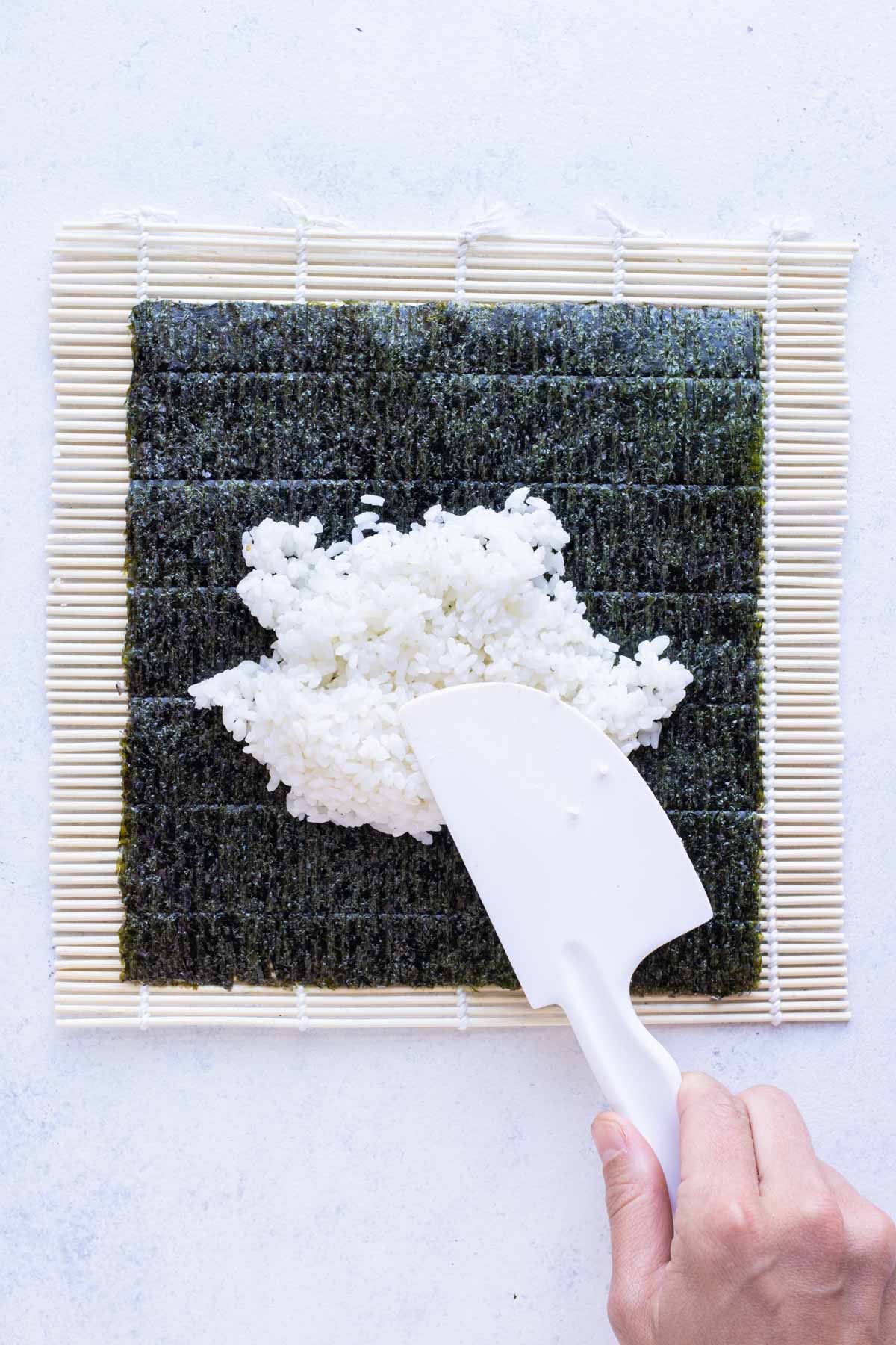 Spatula is used to spread the rice on the nori.