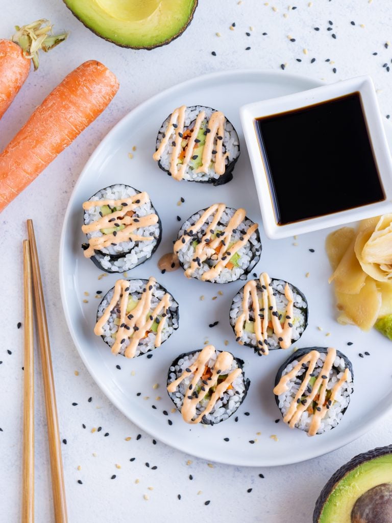 Avocado rolls are served with soy sauce and topped with wasabi.