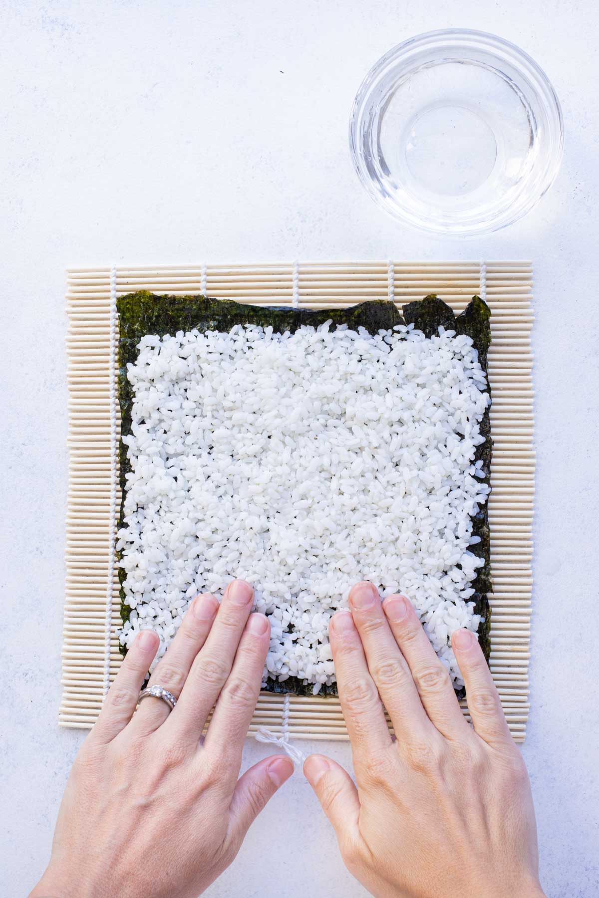 Fingers are wet before spreading the rest of rice evenly.