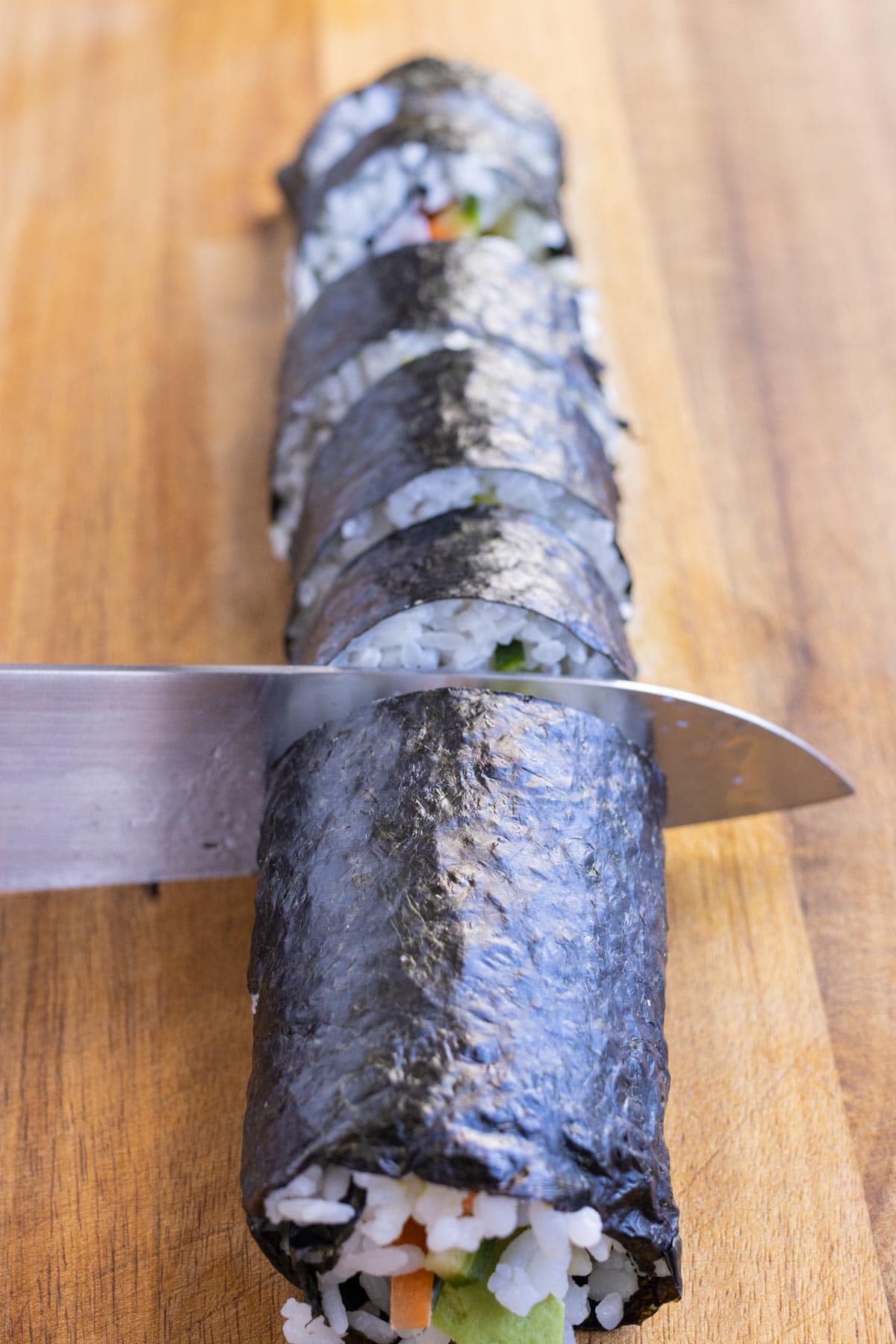 A sharp moist knife is used to cut the sushi roll.