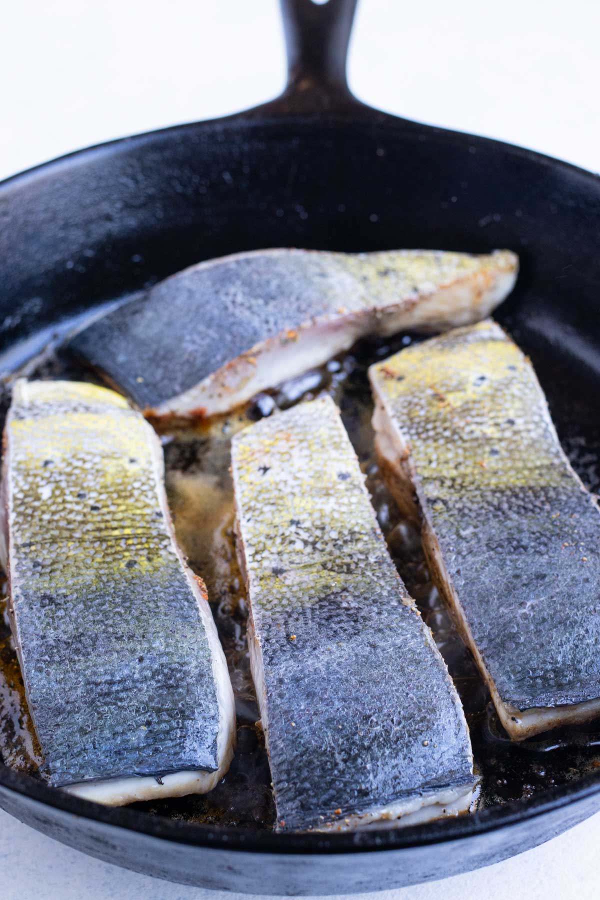 Pieces of Mahi Mahi are cooked in the skillet skin-side up.