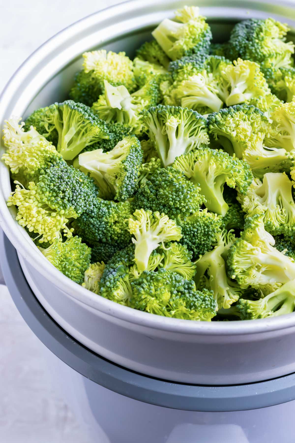 A white bowl of chopped broccoli for creamy broccoli salad.