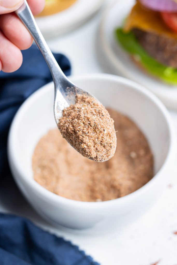 A spoon is shown holding homemade burger seasoning before using.