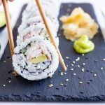Chopsticks are shown picking up a piece of California Roll.