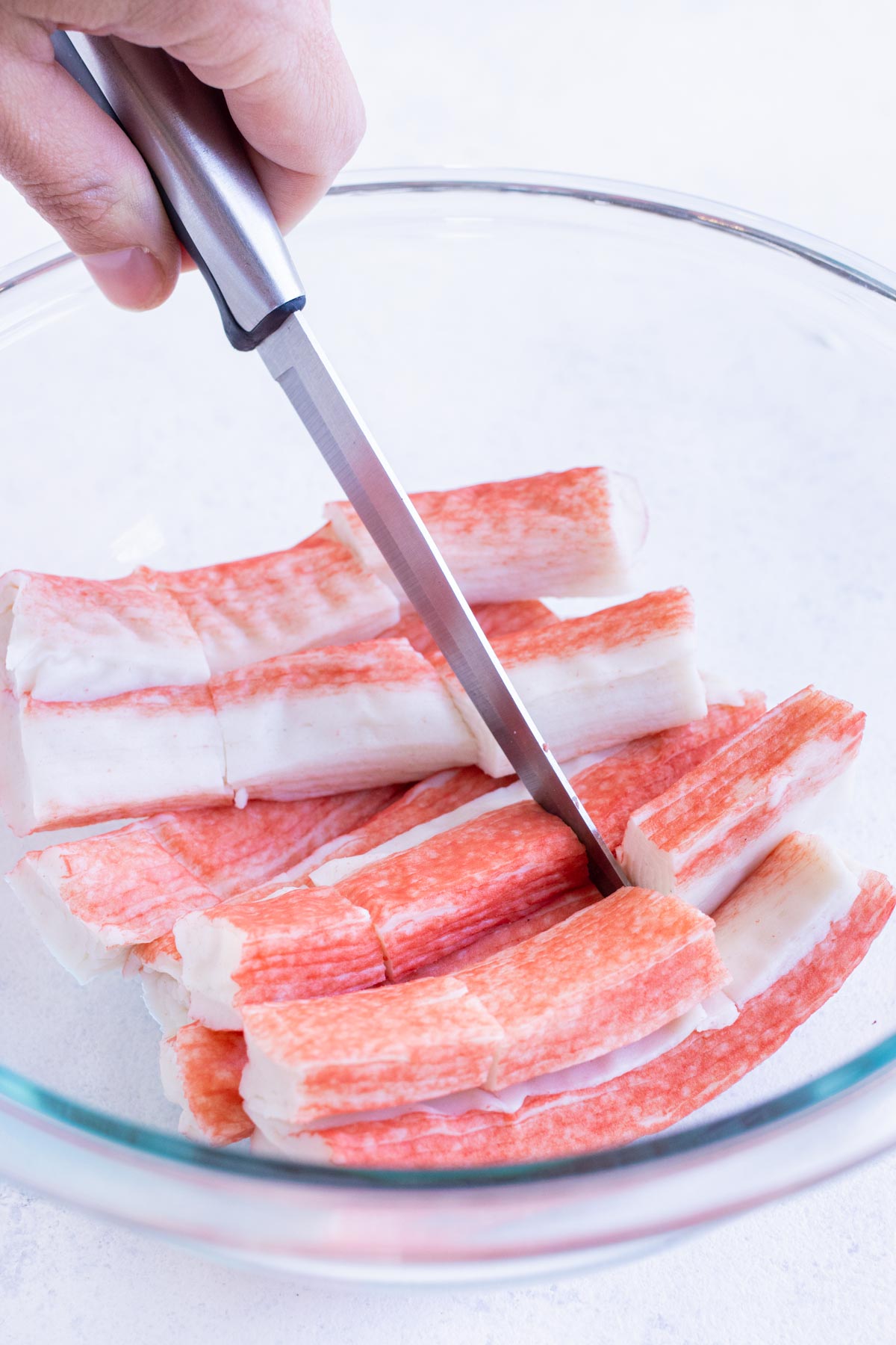 Imitation crab sticks are cut into pieces in a bowl.