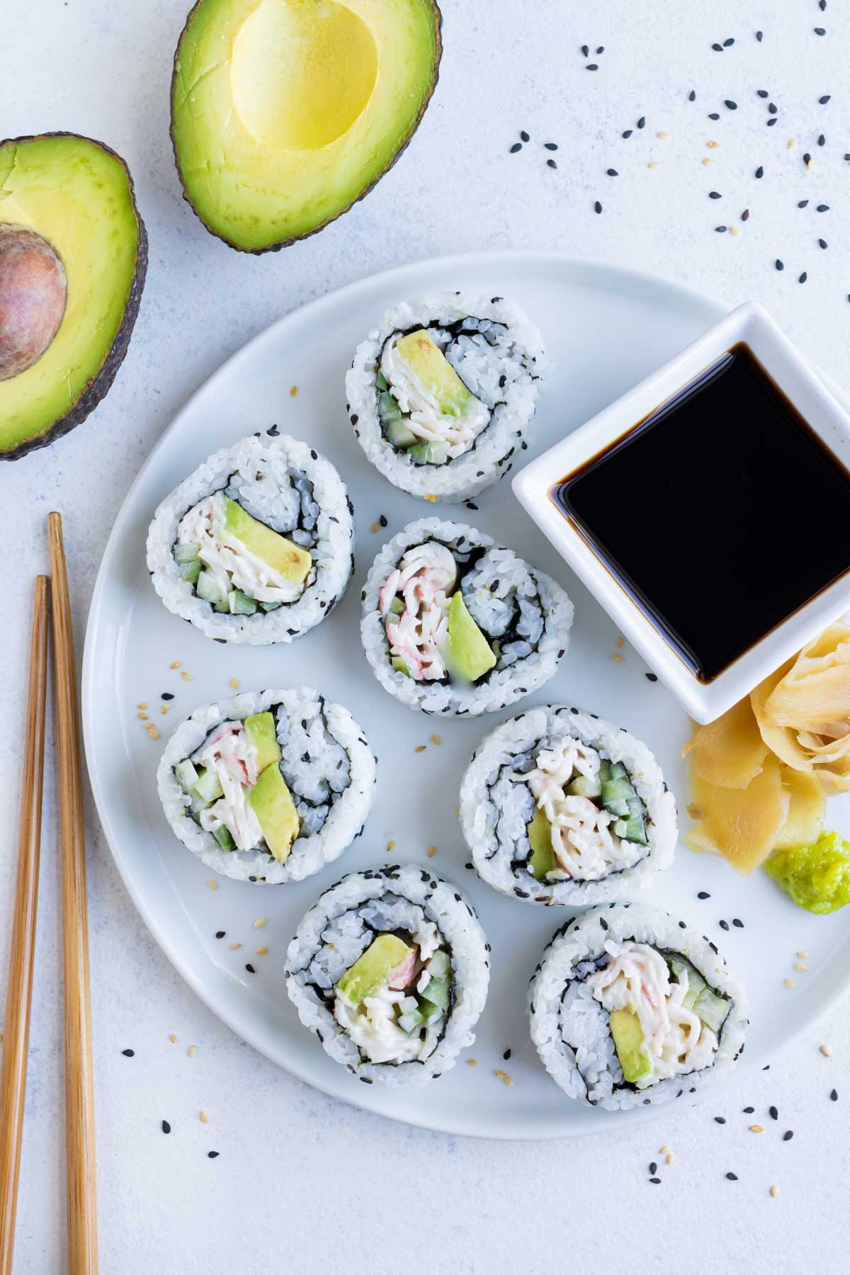 California sushi roll pieces are laid out on a plate with a side of soy sauce.