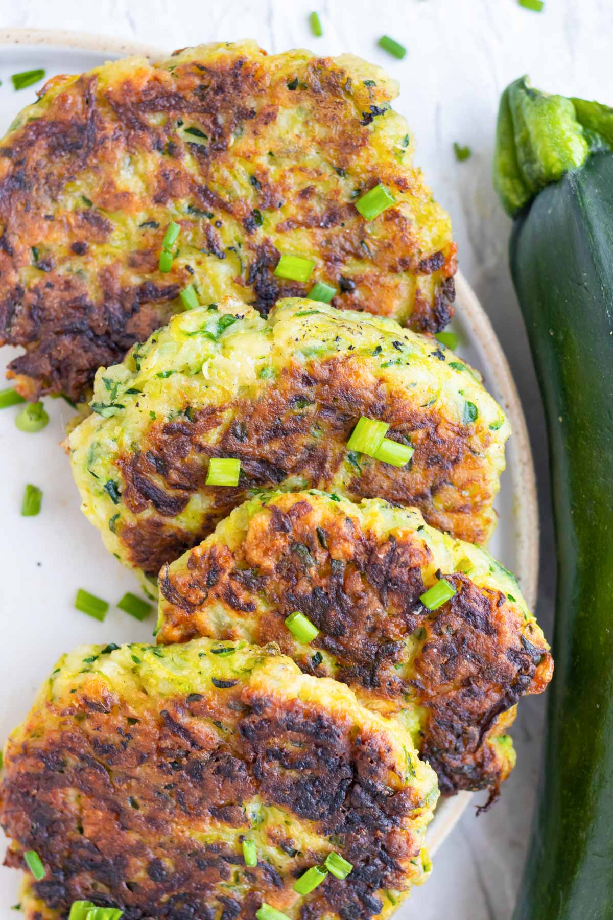 An easy zucchini side dish recipe on a plate next to a zucchini.