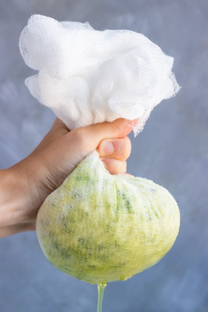 Straining the moisture from shredded zucchini using a cheesecloth.