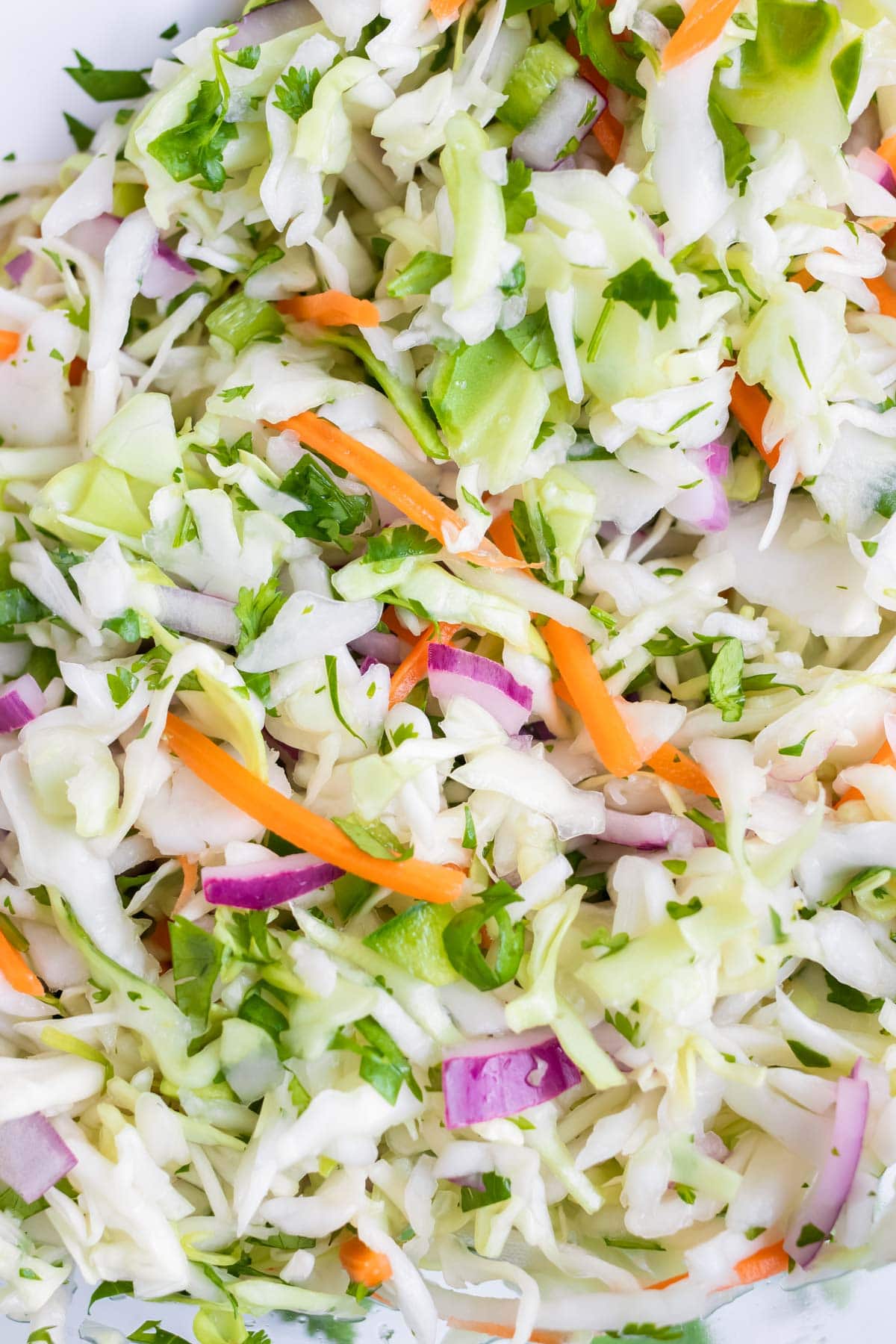 Taco slaw is made with shredded cabbage, red onion, and carrots.