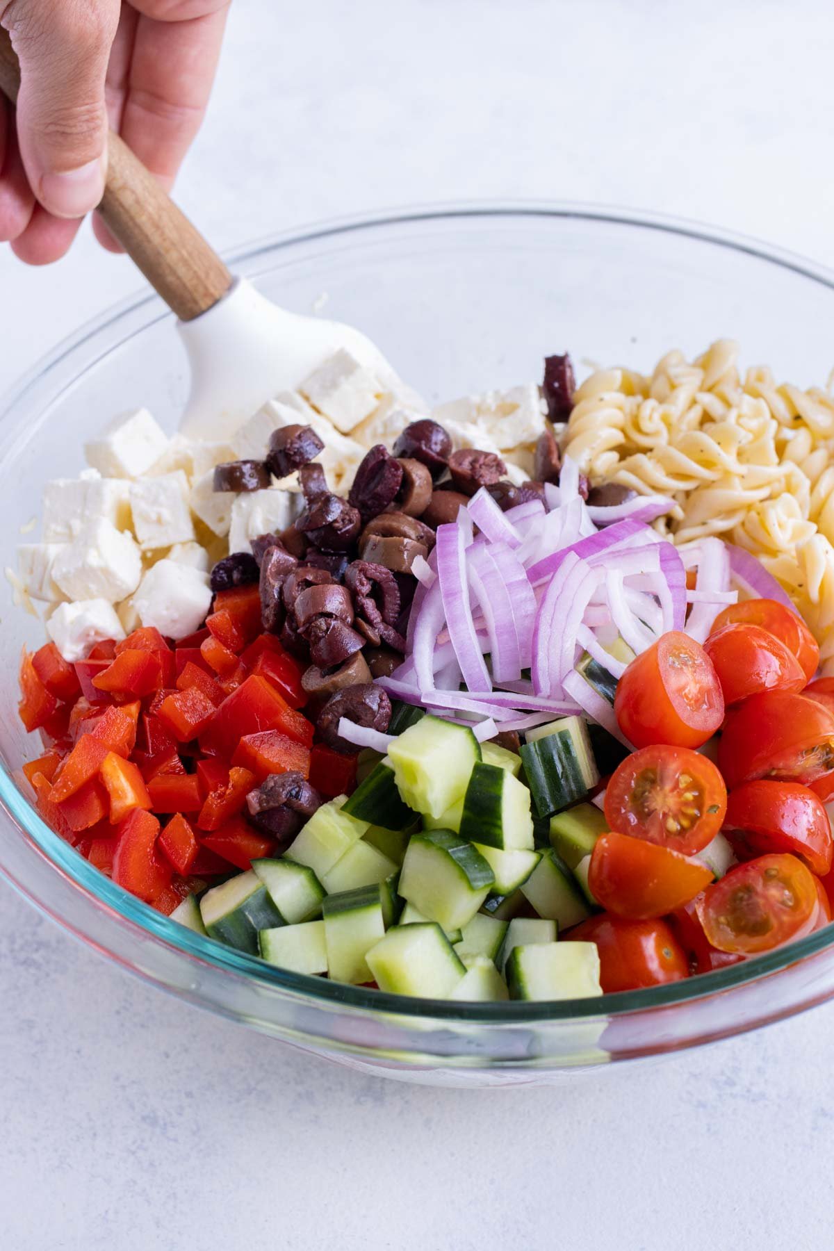 Chopped ingredients are added to the pasta and dressing.