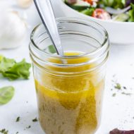 A mason jar filled with greek salad dressing is shown on the counter.