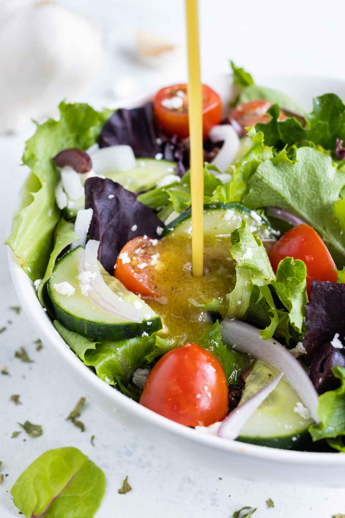Greek salad dressing is poured over a greek salad.