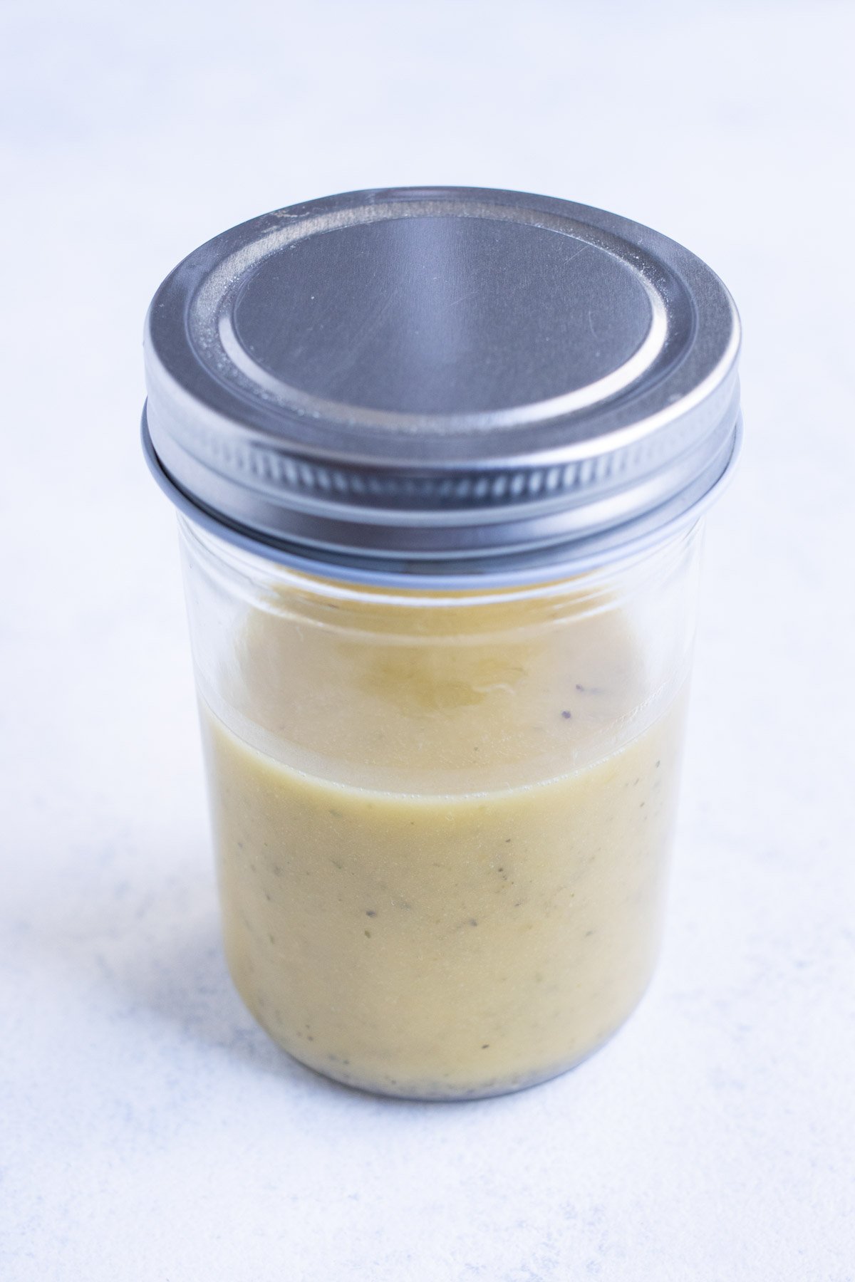 Greek salad dressing is stored in an air tight jar.