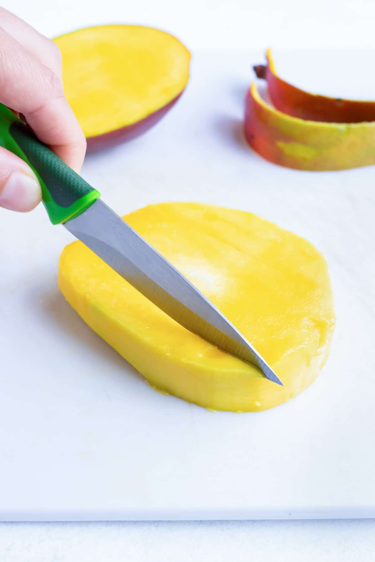 A small paring knife removes the edible mango from around the pit.