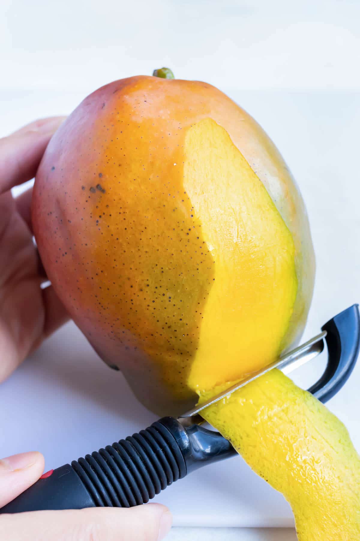 A ripe mango has the skin peeled away.