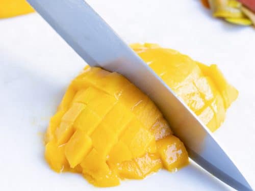 Dicing mango fruit with a knife for a salsa recipe.