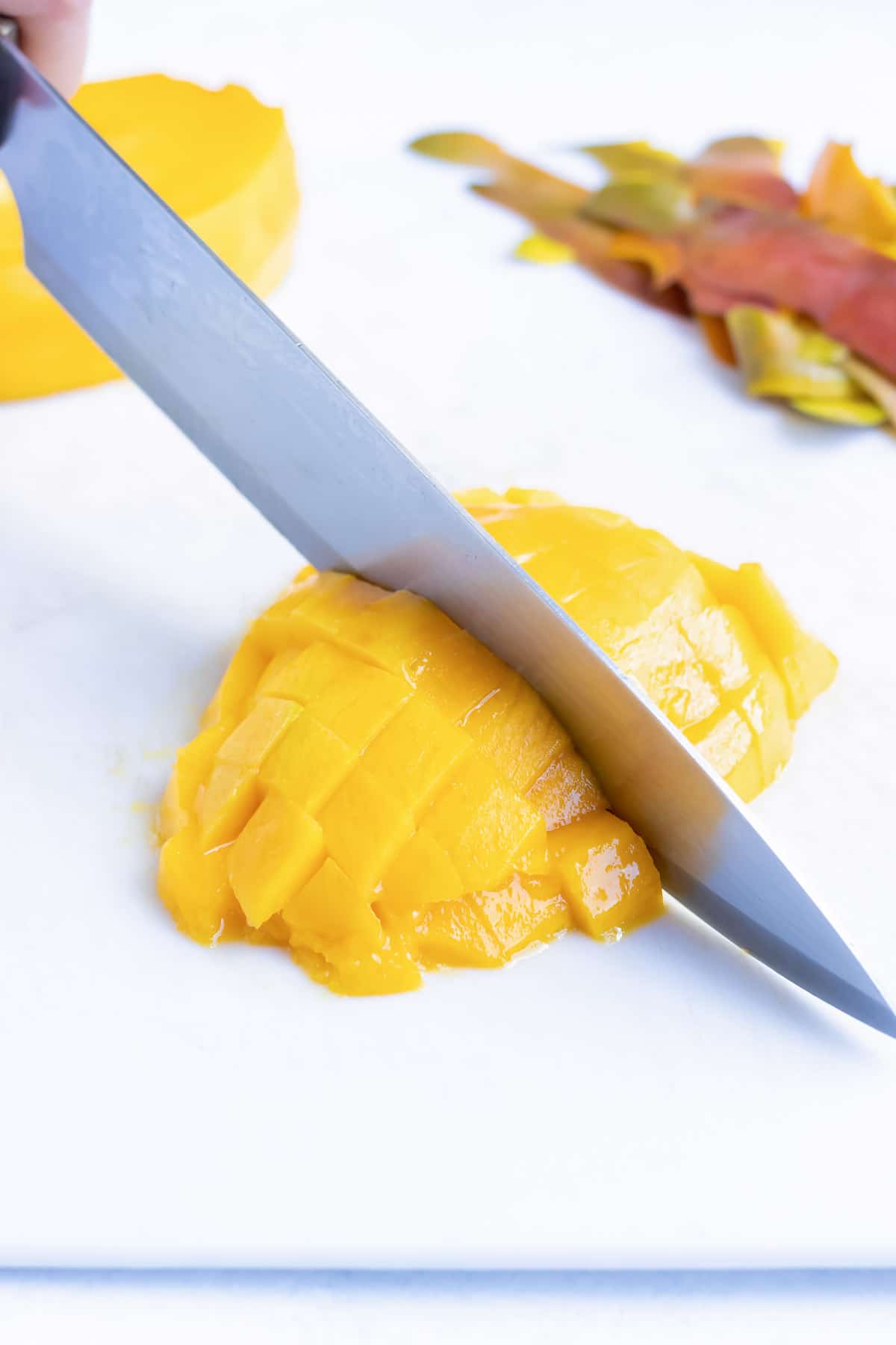 Dicing mango fruit with a knife for a salsa recipe.