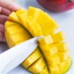 Removing mango pieces with a knife.