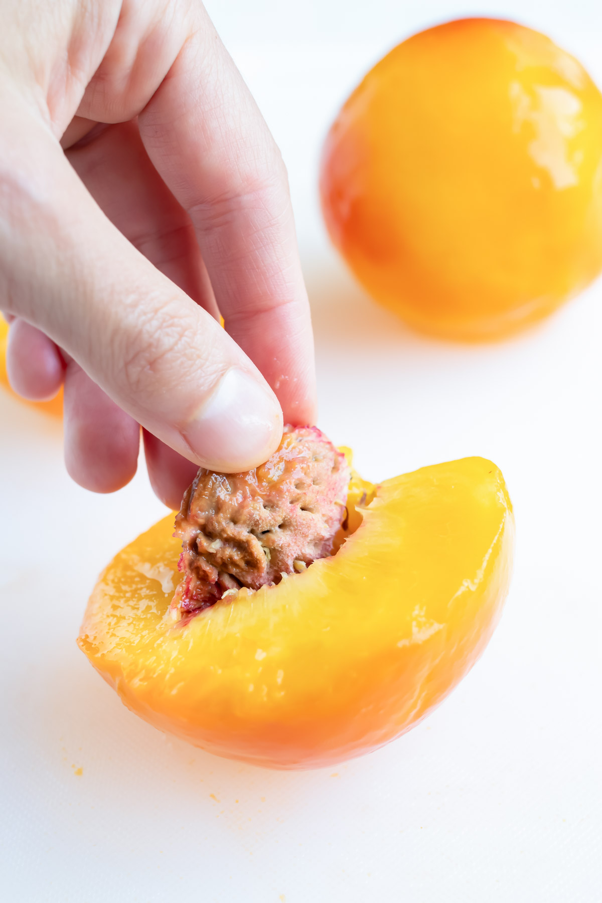 Using your fingers, remove the pit from one side of the peeled peach.