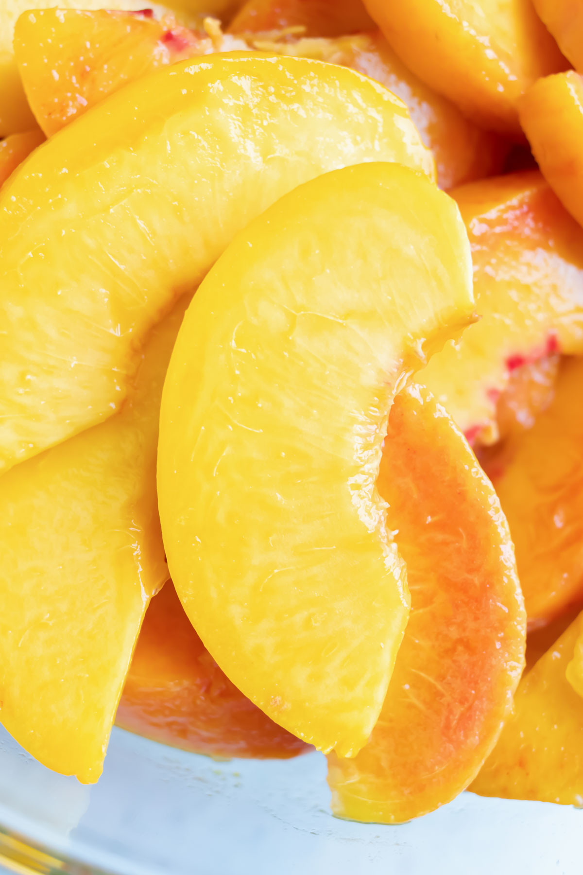 A close up picture of sliced and peeled ripe peaches about a half inch to an inch thick.
