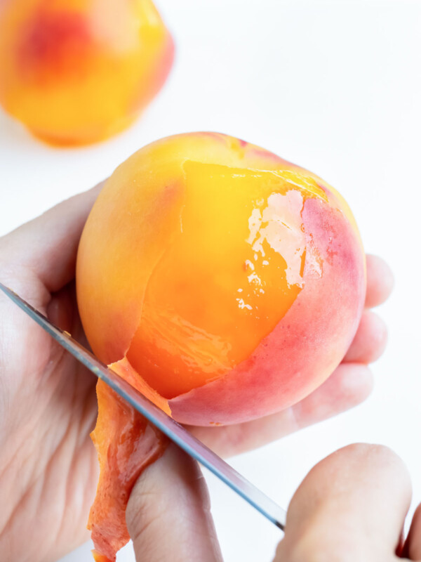 Using a paring knife, peel back the skin of the peach in your hand.