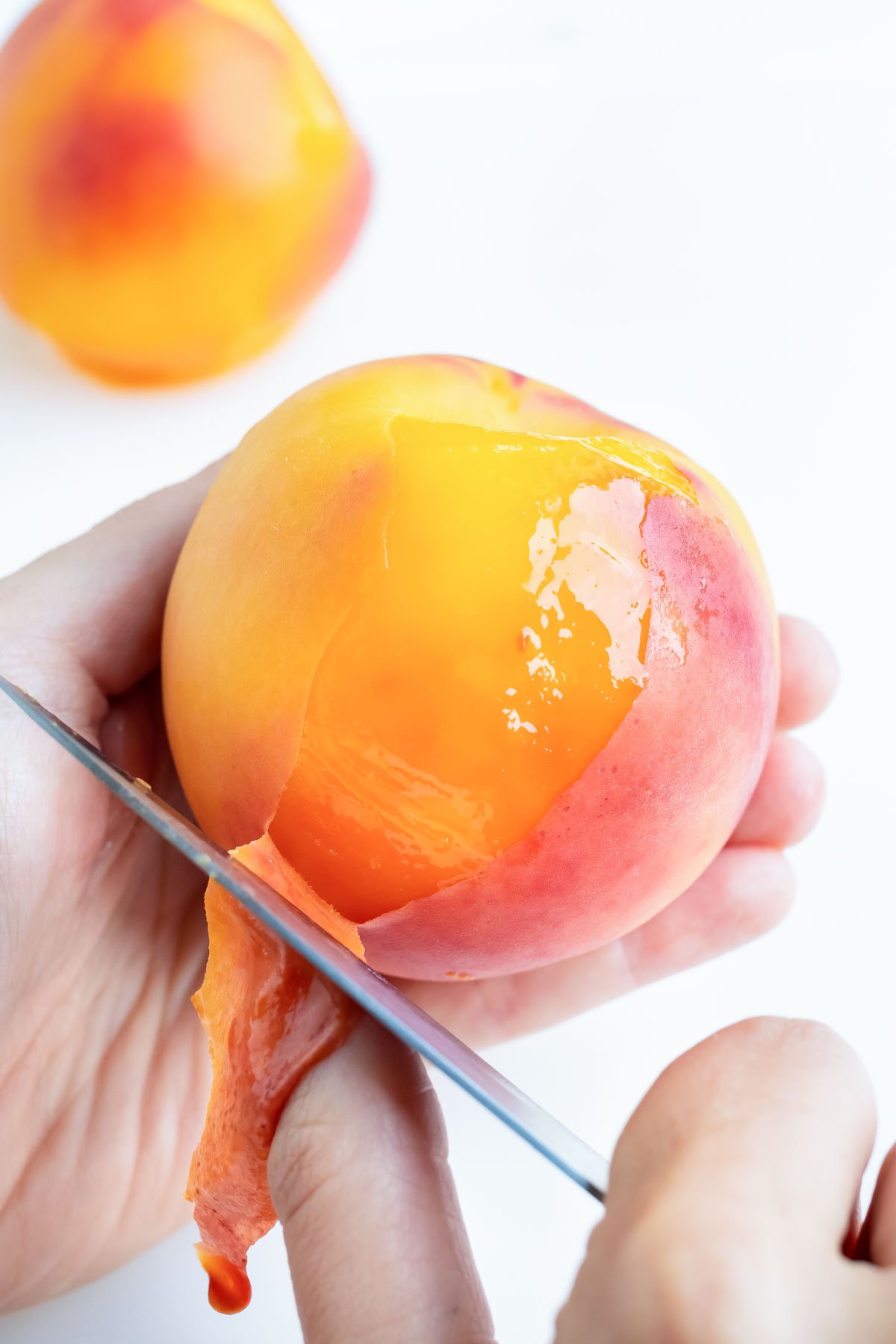 Using a paring knife, peel back the skin of the peach in your hand.