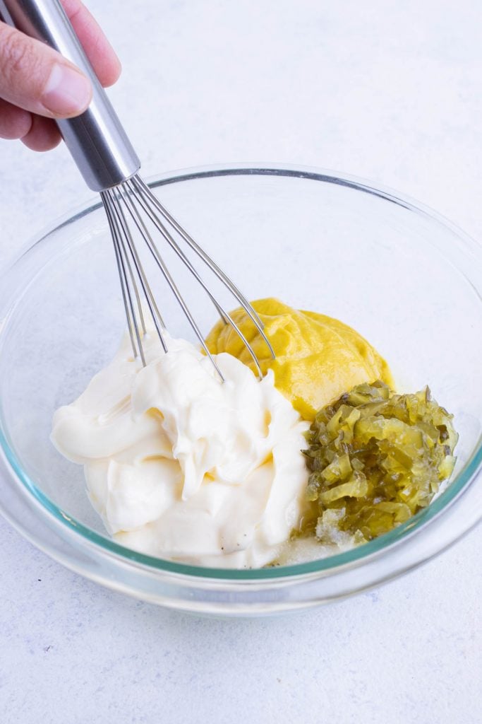 Mayonnaise, yellow mustard, and dill pickle relish in a bowl for potato salad dressing.