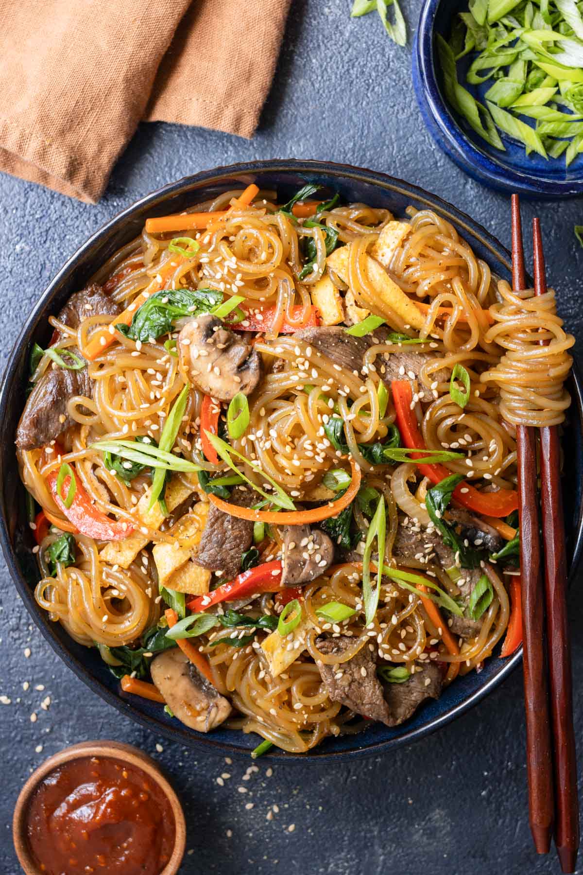 A bowl of Japchae is served alongside chopsticks for digging in.