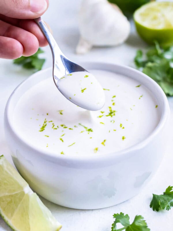 A spoon is used to serve this homemade lime crema recipe as a fish taco sauce.