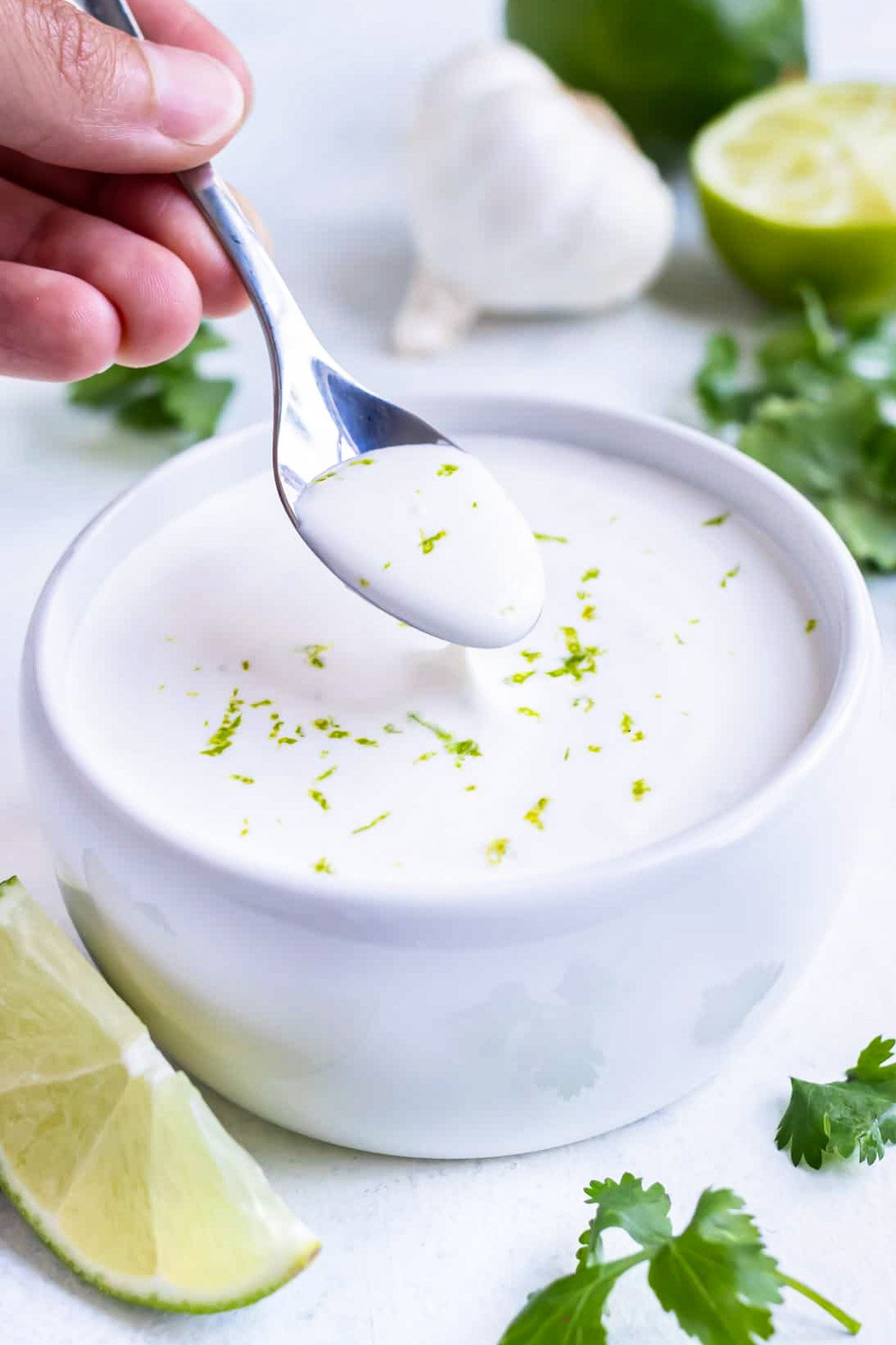 A spoon is used to serve this homemade lime crema recipe as a fish taco sauce.