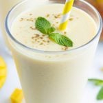 A glass is filled with a smooth and creamy Mango Lassi recipe with a straw.