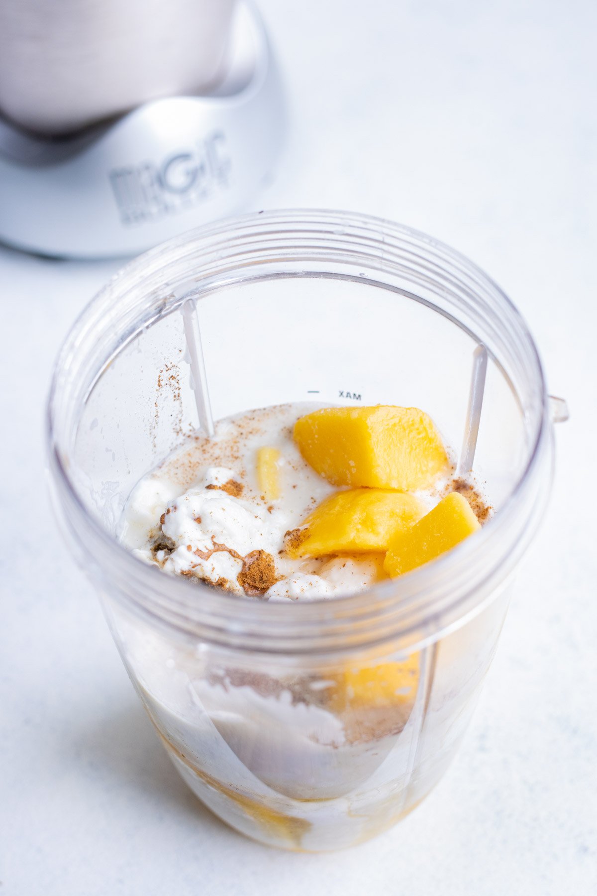 Mango, yogurt, milk, spices, and honey are added to the blender.