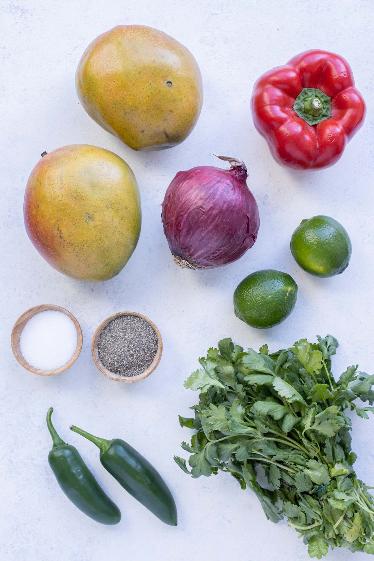 Mangos, cilantro, limes, red onions, bell peppers, jalapeños, salt, and pepper are the ingredients in this recipe.