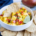 Mango salsa is served with chips and fresh limes.
