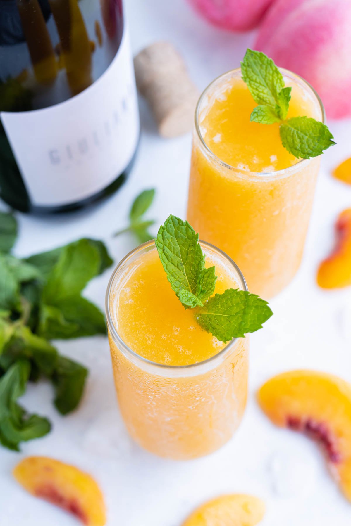 Two flutes with Peach Bellinis and a sprig of mint.