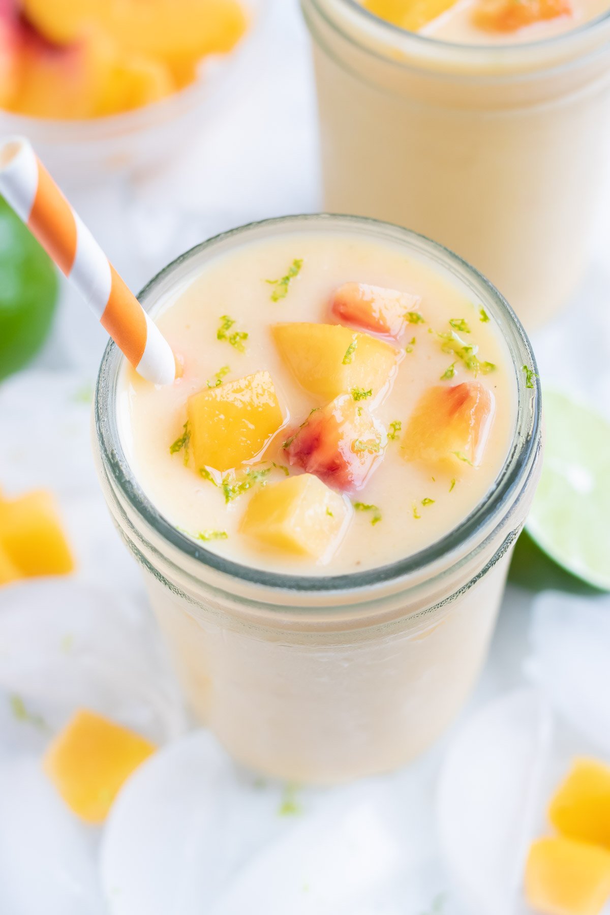 Thick and creamy peach shake is served in a glass cup with a straw.
